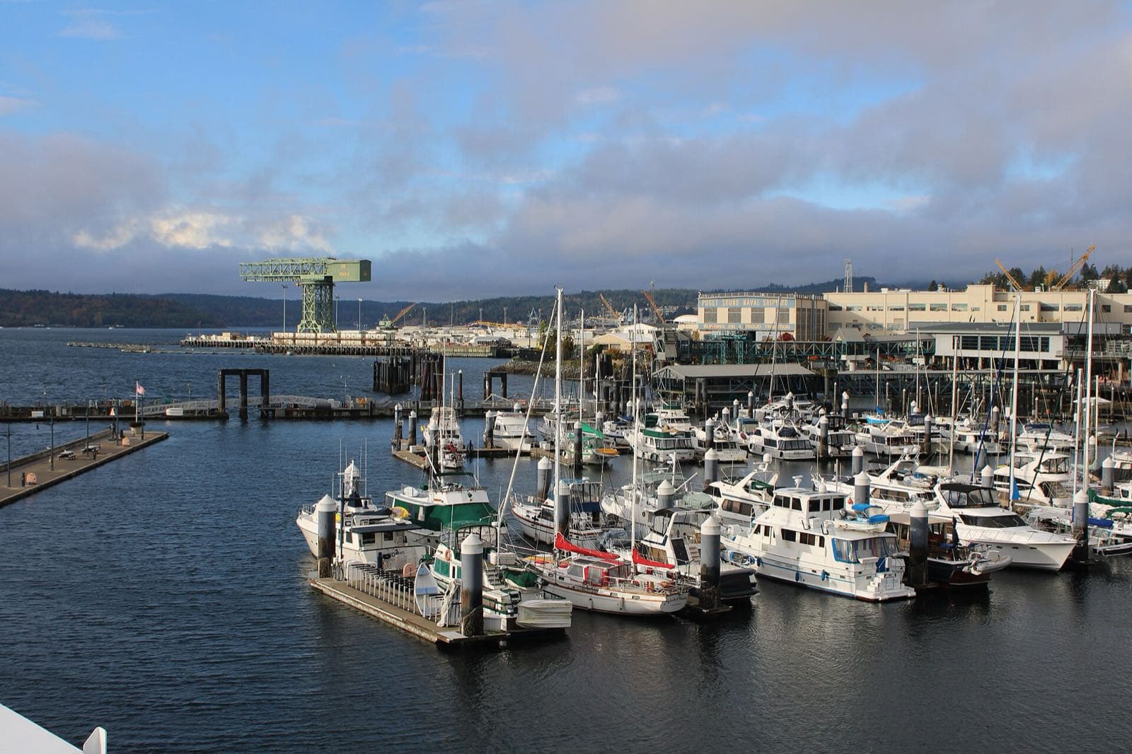 Boats in the Bremerton marina on Sinclair Inlet, with the waterfront and the shipyard's hammerhead crane beyond.