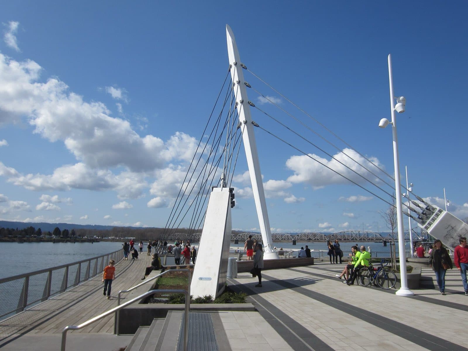 People strolling the Grant Street Pier on the Vancouver, Washington waterfront under a bright sky.