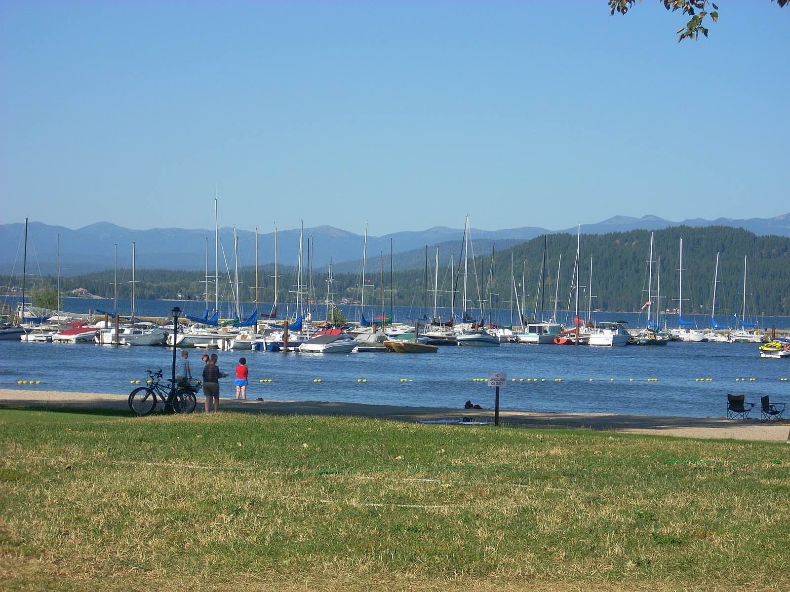 Sailboats in the Sandpoint marina on Lake Pend Oreille, with forested mountains on the far shore.