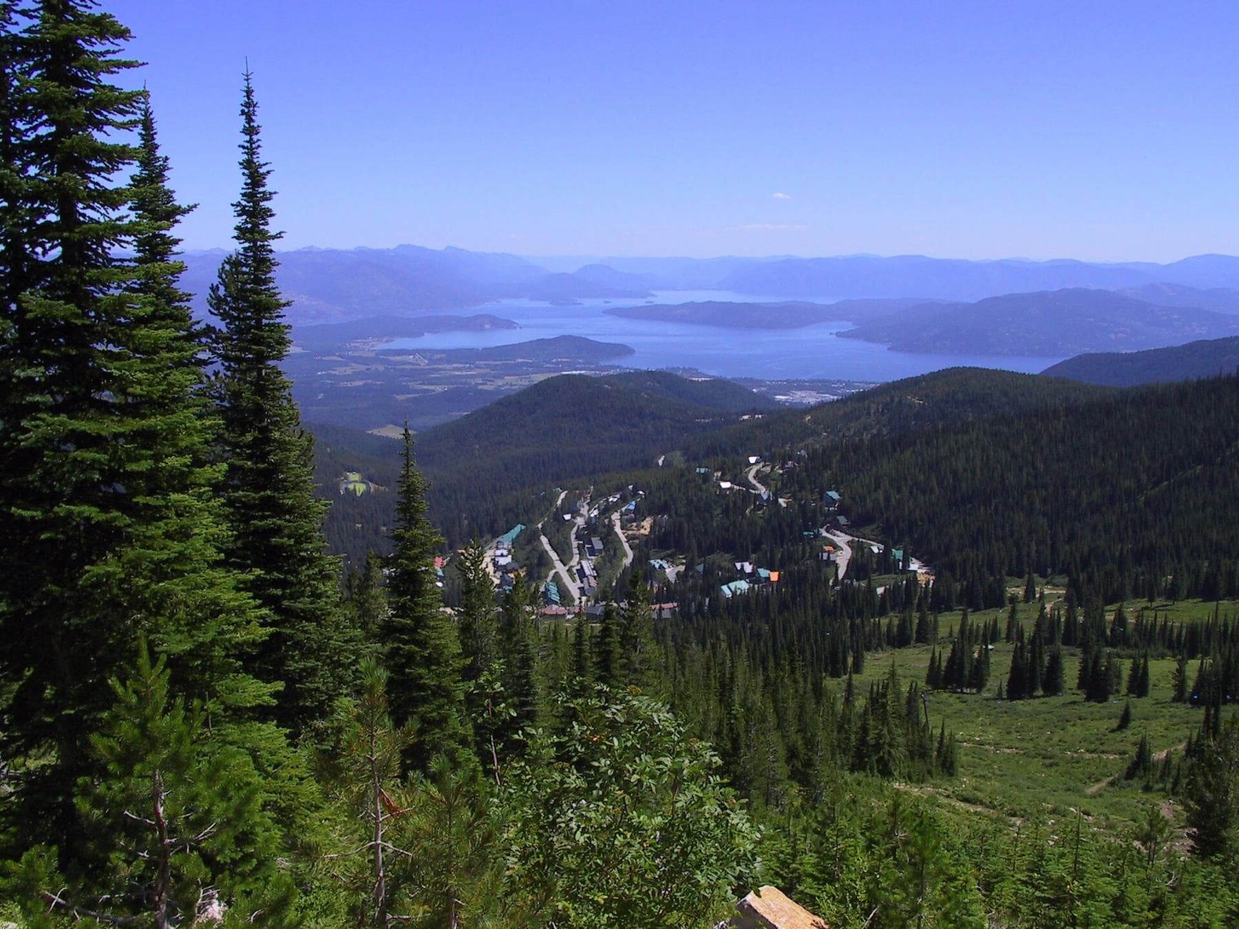 View from Schweitzer Mountain over the resort village and evergreen slopes to Sandpoint and Lake Pend Oreille.